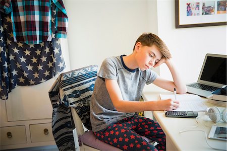 preteen pyjama - Bored boy doing math homework at desk in bedroom Stock Photo - Premium Royalty-Free, Code: 6113-08655411