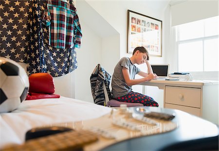 Bored boy doing homework at desk in bedroom Fotografie stock - Premium Royalty-Free, Codice: 6113-08655428