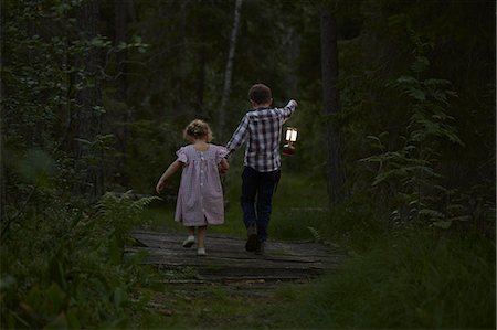 friluftsliv - Brother and sister walking with lantern over footbridge in woods Stock Photo - Premium Royalty-Free, Code: 6113-08698066