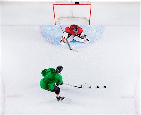 simsearch:6113-08698170,k - Overhead view hockey player practicing with goalie shooting puck at goal net Stock Photo - Premium Royalty-Free, Code: 6113-08698173