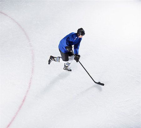 simsearch:6113-08698170,k - Hockey player in blue uniform skating with puck on ice Stock Photo - Premium Royalty-Free, Code: 6113-08698178