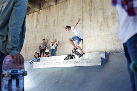 simsearch:649-07710443,k - Friends watching and cheering teenage boy skateboarding at skate park Stock Photo - Premium Royalty-Free, Code: 6113-08698195