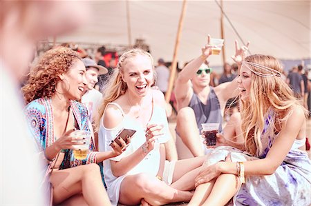 Young women hanging out drinking at sunny music festival Stock Photo - Premium Royalty-Free, Code: 6113-08698295