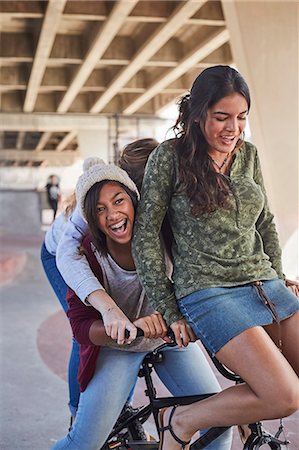 simsearch:6113-06899255,k - Playful teenage girls riding BMX bicycle at skate park Stock Photo - Premium Royalty-Free, Code: 6113-08698230