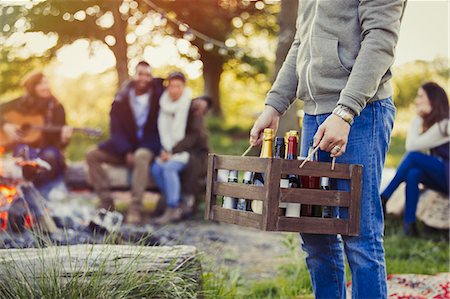 simsearch:6113-08743597,k - Man carrying crate of wine and beer at campsite with friends Stock Photo - Premium Royalty-Free, Code: 6113-08743396