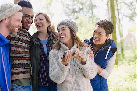 sharing - Smiling friends hiking using cell phone in woods Stock Photo - Premium Royalty-Free, Code: 6113-08743474