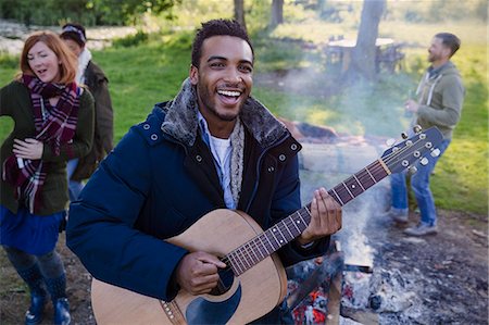 simsearch:614-06719795,k - Portrait smiling man playing guitar with friends at campsite Stock Photo - Premium Royalty-Free, Code: 6113-08743491
