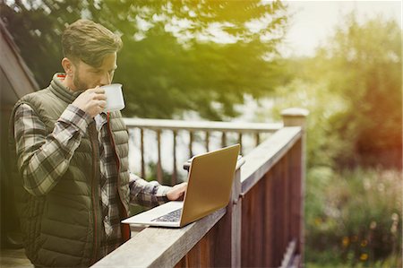 Man drinking coffee and using laptop on cabin deck Stock Photo - Premium Royalty-Free, Code: 6113-08743404