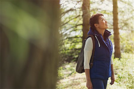 simsearch:6113-08743597,k - Woman hiking with backpack looking up in woods Stock Photo - Premium Royalty-Free, Code: 6113-08743421