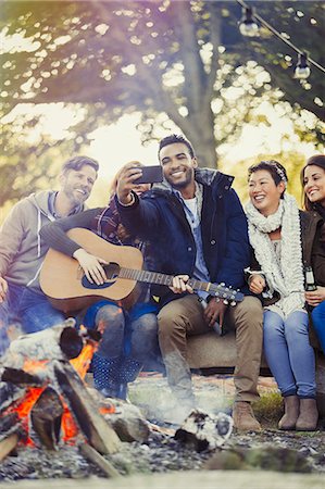 simsearch:6113-08743597,k - Friends with guitar taking selfie with camera phone at campfire Stock Photo - Premium Royalty-Free, Code: 6113-08743429