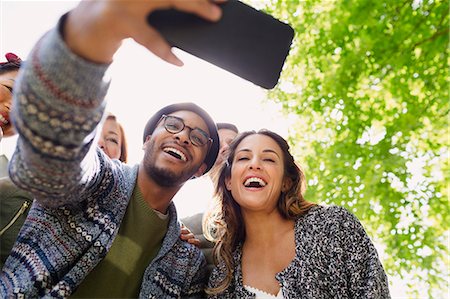 simsearch:6113-08743597,k - Enthusiastic friends taking selfie with camera phone below tree Stock Photo - Premium Royalty-Free, Code: 6113-08743502