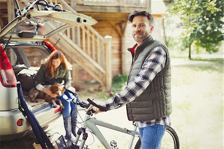 simsearch:6113-06754093,k - Portrait smiling man with mountain bike near car behind cabin Foto de stock - Sin royalties Premium, Código: 6113-08743510