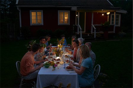 people sitting at a table - Family enjoying candlelight dinner at patio table outside house at night Stock Photo - Premium Royalty-Free, Code: 6113-08743606