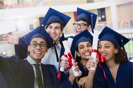 education - Happy college students in cap and gown holding diplomas posing for selfie Photographie de stock - Premium Libres de Droits, Code: 6113-08769703