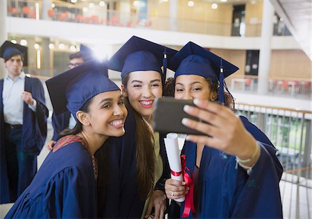 Female college graduates in cap and gown taking selfie Stock Photo - Premium Royalty-Free, Code: 6113-08769714