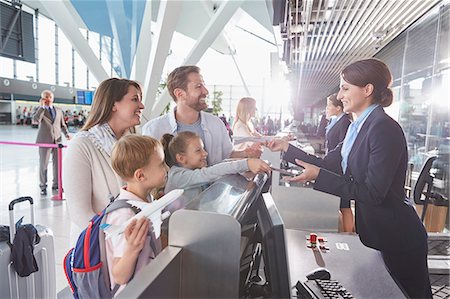 Customer service representative checking family tickets at airport check-in counter Stock Photo - Premium Royalty-Free, Code: 6113-08784148