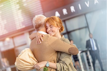 Husband and wife with flowers greeting and hugging in airport Stock Photo - Premium Royalty-Free, Code: 6113-08784149