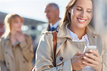 Smiling businesswoman texting with cell phone Stock Photo - Premium Royalty-Free, Code: 6113-08784244