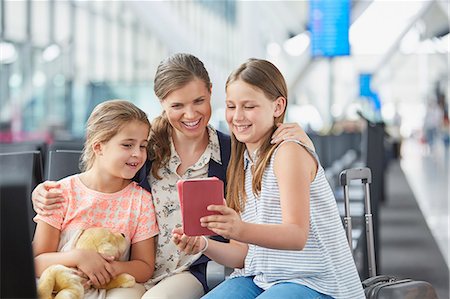 Mother and daughters using digital tablet in airport departure area Stock Photo - Premium Royalty-Free, Code: 6113-08784260