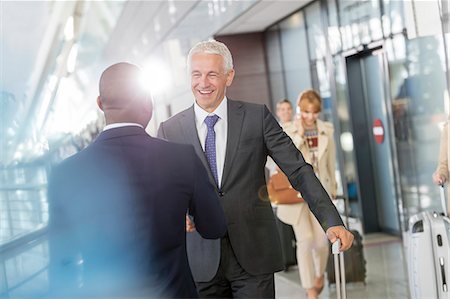 Businessmen greeting in airport concourse Stock Photo - Premium Royalty-Free, Code: 6113-08784212