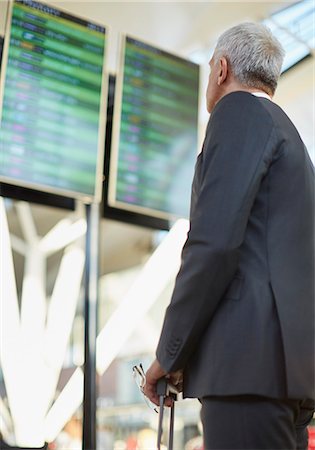 Businessman looking up at airport arrival departure board Stock Photo - Premium Royalty-Free, Code: 6113-08784318