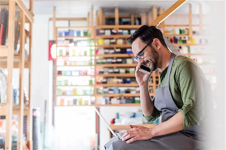 small business owner on phone - Stained glass artist talking on cell phone and using laptop in studio Stock Photo - Premium Royalty-Free, Code: 6113-08784337