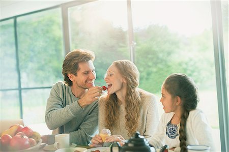simsearch:6113-06720252,k - Husband feeding wife strawberry at table Stock Photo - Premium Royalty-Free, Code: 6113-08722045