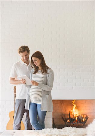 simsearch:6113-07762308,k - Pregnant couple using digital tablet near fireplace Stock Photo - Premium Royalty-Free, Code: 6113-08722088
