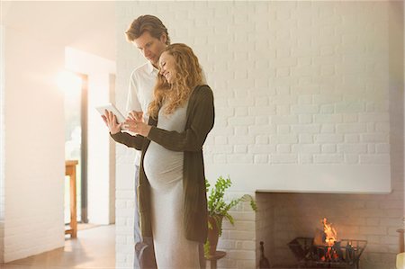 simsearch:6113-07762308,k - Pregnant couple using digital tablet near fireplace in living room Stock Photo - Premium Royalty-Free, Code: 6113-08722003