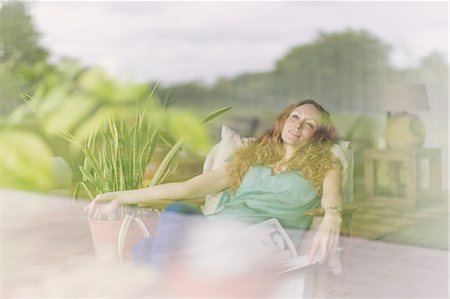 simsearch:6113-06909277,k - Comfortable woman relaxing in armchair at living room window Stock Photo - Premium Royalty-Free, Code: 6113-08722008