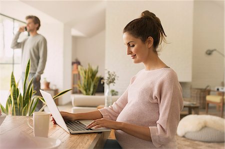 Pregnant woman using laptop at dining table Stock Photo - Premium Royalty-Free, Code: 6113-08722034