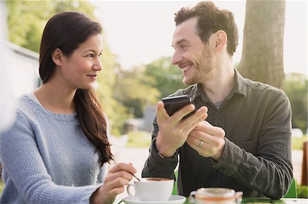 simsearch:6113-08743448,k - Couple with cell phone drinking coffee at outdoor cafe Stock Photo - Premium Royalty-Free, Code: 6113-08722155