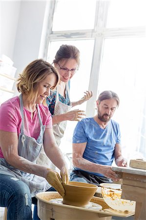 Teacher guiding mature couple using pottery wheel in studio Stock Photo - Premium Royalty-Free, Code: 6113-08722449