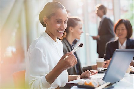 simsearch:614-02985267,k - Smiling businesswoman eating sushi lunch with chopstick at laptop in conference room meeting Stock Photo - Premium Royalty-Free, Code: 6113-08882448