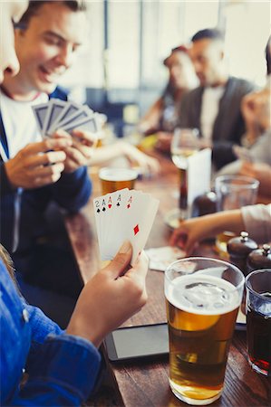 Woman holding aces four of a kind playing poker and drinking beer with friends at bar Stock Photo - Premium Royalty-Free, Code: 6113-08882595