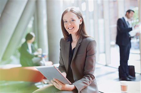simsearch:6113-07243187,k - Portrait smiling businesswoman using digital tablet in sunny office lobby Stock Photo - Premium Royalty-Free, Code: 6113-08882510