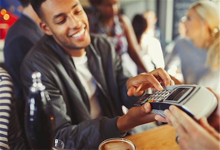 Smiling man paying bartender using credit card reader at bar Stock Photo - Premium Royalty-Free, Code: 6113-08882634