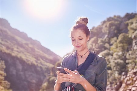 sunflare nature - Young woman texting with cell phone below sunny cliffs Photographie de stock - Premium Libres de Droits, Code: 6113-08882768