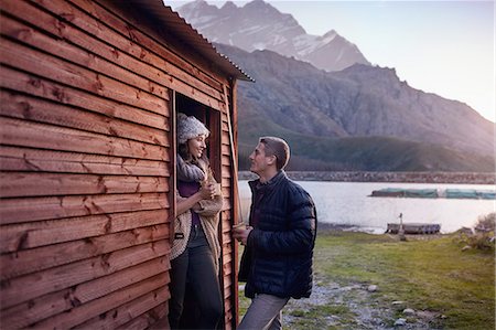 Young couple drinking coffee at lakeside cabin doorway Stock Photo - Premium Royalty-Free, Code: 6113-08882772