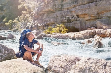 simsearch:632-05604251,k - Young man with backpack hiking, resting at sunny, craggy stream Photographie de stock - Premium Libres de Droits, Code: 6113-08882787