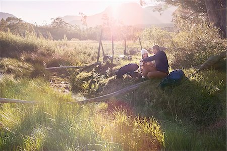 simsearch:632-05604251,k - Young couple with backpacks hiking, resting in sunny remote field Photographie de stock - Premium Libres de Droits, Code: 6113-08882818