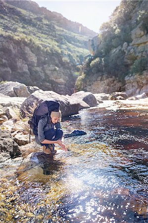 simsearch:632-05604251,k - Young woman with backpack hiking, washing hands at sunny stream Photographie de stock - Premium Libres de Droits, Code: 6113-08882828