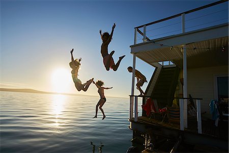 simsearch:6113-06899255,k - Young adult friends jumping off summer houseboat into sunset ocean Stock Photo - Premium Royalty-Free, Code: 6113-08805283