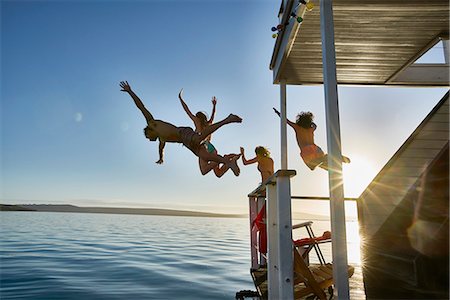 simsearch:6113-07146985,k - Young adult friends jumping from summer houseboat into sunny ocean Foto de stock - Sin royalties Premium, Código: 6113-08805295