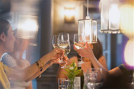 people sitting in restaurants - Women friends toasting white wine glasses dining at restaurant table Stock Photo - Premium Royalty-Free, Code: 6113-08805357