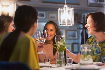 simsearch:6113-08659553,k - Smiling women friends toasting white wine glasses dining at restaurant table Stock Photo - Premium Royalty-Free, Code: 6113-08805318