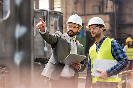 Manager and steel worker talking and looking away in factory Stock Photo - Premium Royalty-Free, Code: 6113-08805570