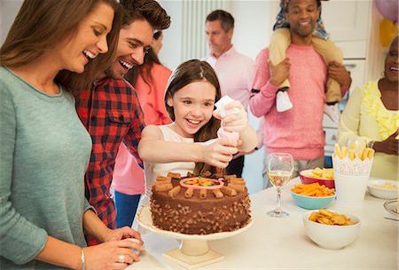 family holiday party - Smiling family icing chocolate cake in kitchen Stock Photo - Premium Royalty-Free, Code: 6113-08805678