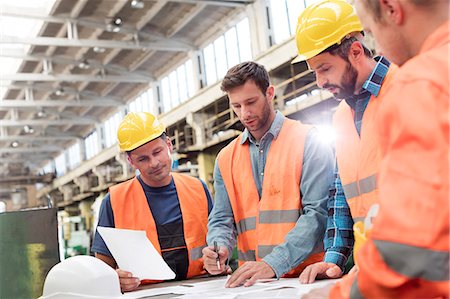 Steel workers and engineers meeting reviewing blueprints in factory Stock Photo - Premium Royalty-Free, Code: 6113-08805619