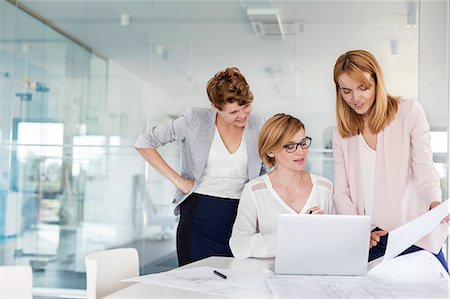 simsearch:6113-08105522,k - Female architects at laptop reviewing blueprints in conference room meeting Foto de stock - Sin royalties Premium, Código: 6113-08805756